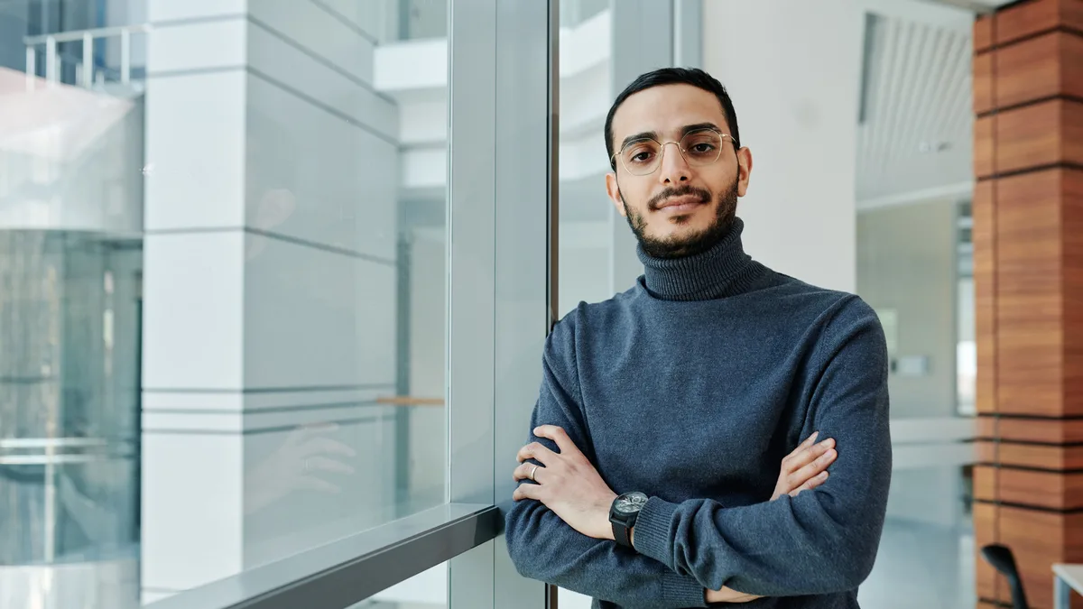 A business owner standing by a window, ready with questions about the GoHighLevel affiliate program