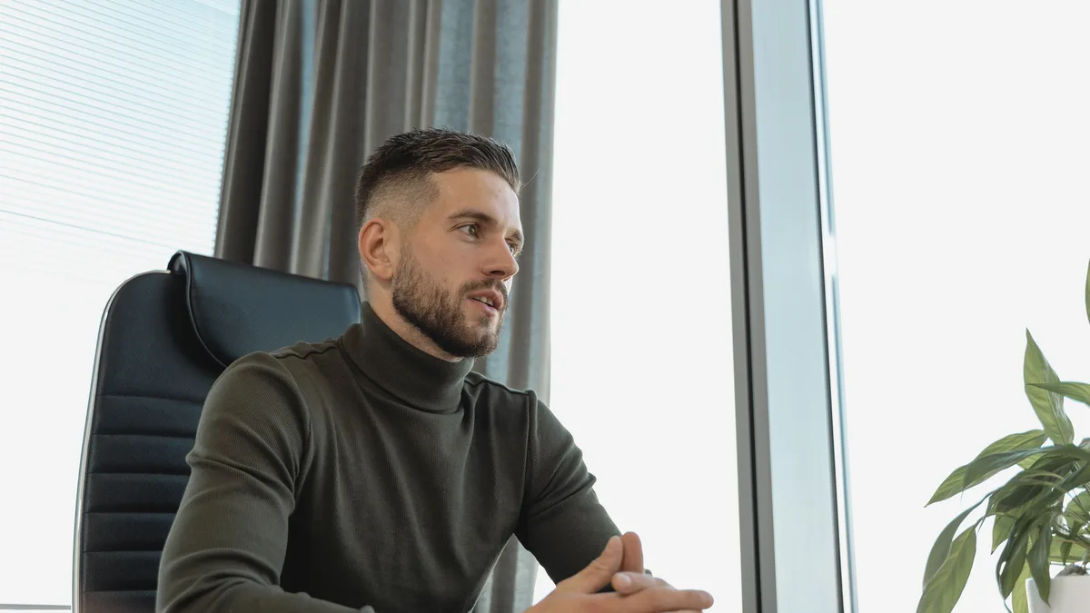 A business owner sitting by a window, weighing questions about the GoHighLevel affiliate program