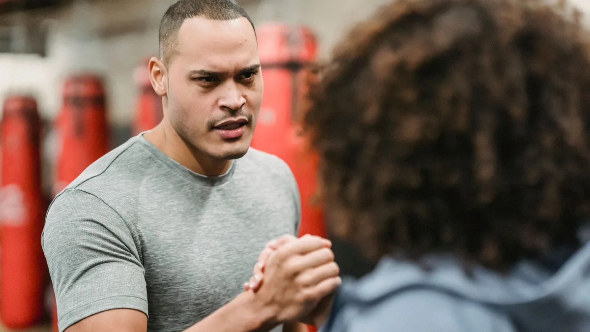 A gym coach and a visitor sharing a fist bump in a studio, representing a friendly talk about GoHighLevel for gyms