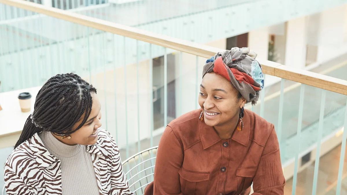 Two businesswomen talking over coffee at a bright table about GoHighLevel plans