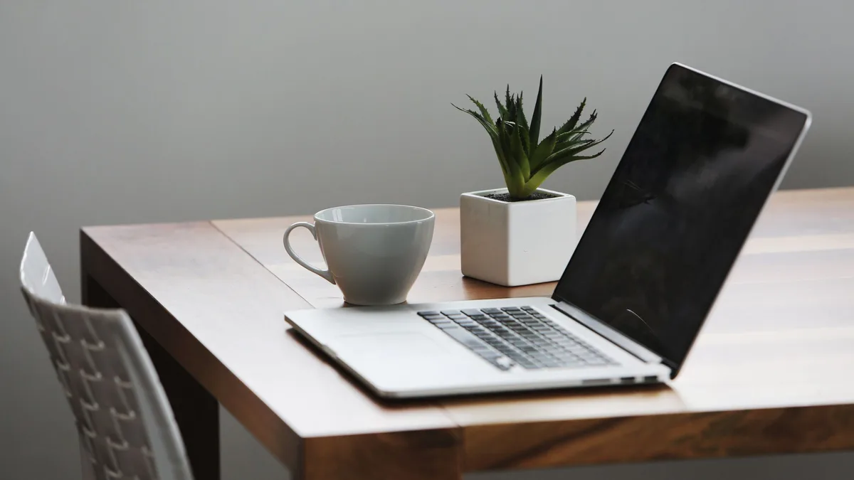 A single laptop, coffee mug and succulent on a desk, representing GoHighLevel plans for one business