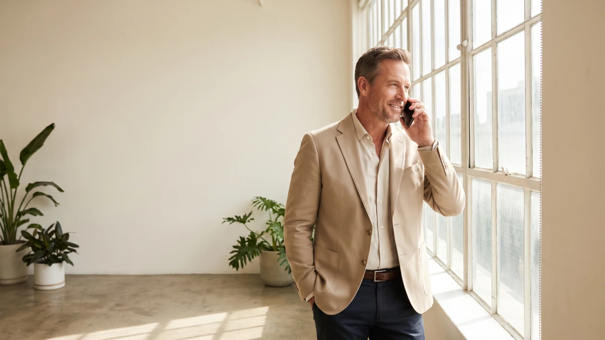Business owner on the phone by a tall window, GoHighLevel pricing questions answered