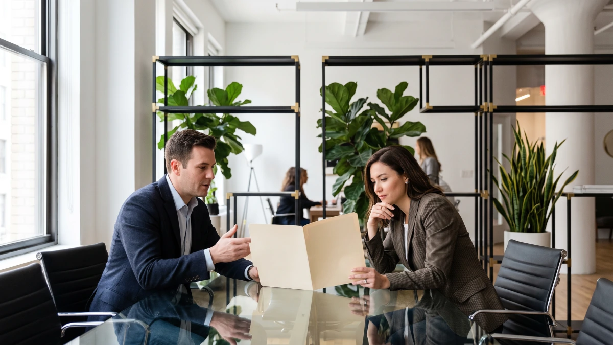 Two professionals at a glass table discussing how an agency resells GoHighLevel pricing