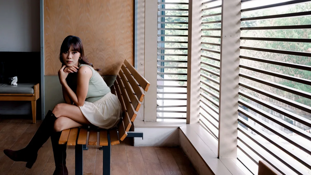 A business owner on a bench by a window, considering common questions about phone number porting