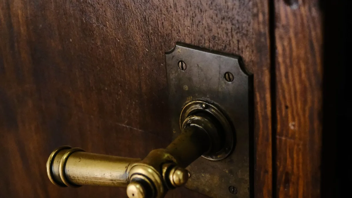 A closed wooden door with a brass handle, representing a stalled phone number porting request