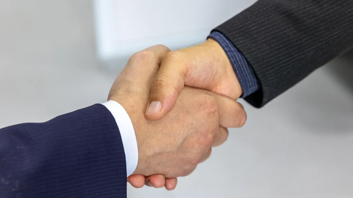 A close-up handshake between two professionals, representing an agreement on a sub-account transfer