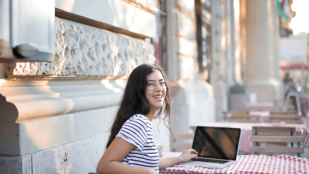 A business owner at an outdoor cafe table with her laptop, from our GHL contact first name guide