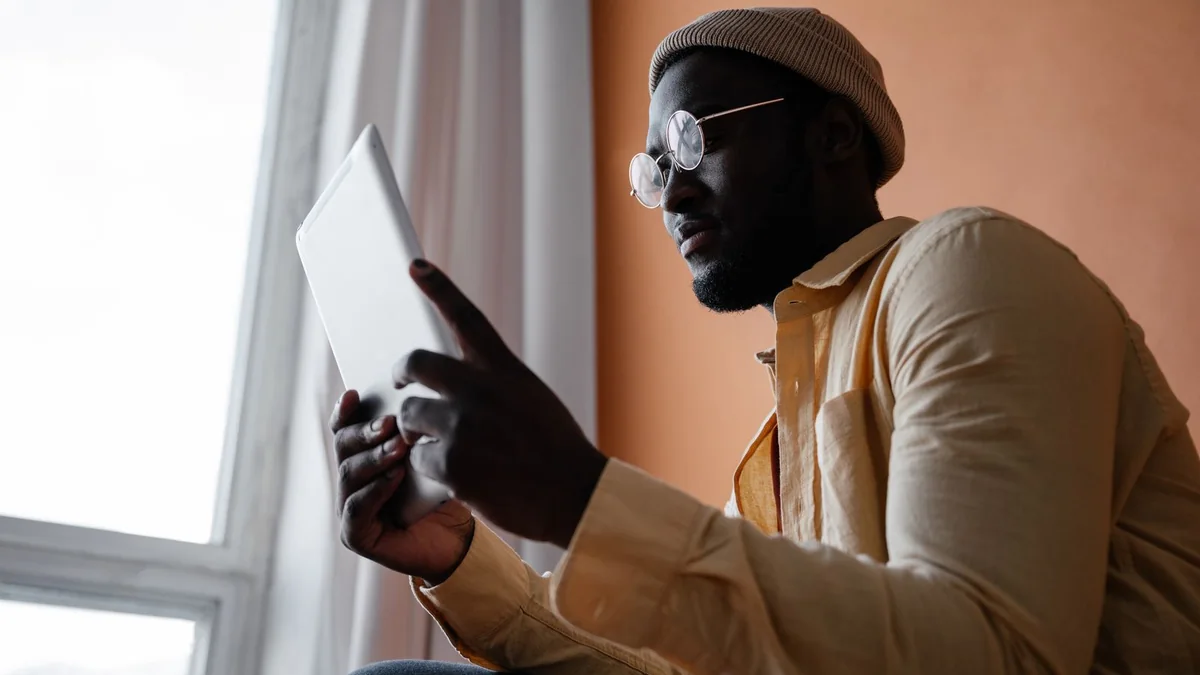 A business owner taps a tablet by the window, from our GHL contact first name guide