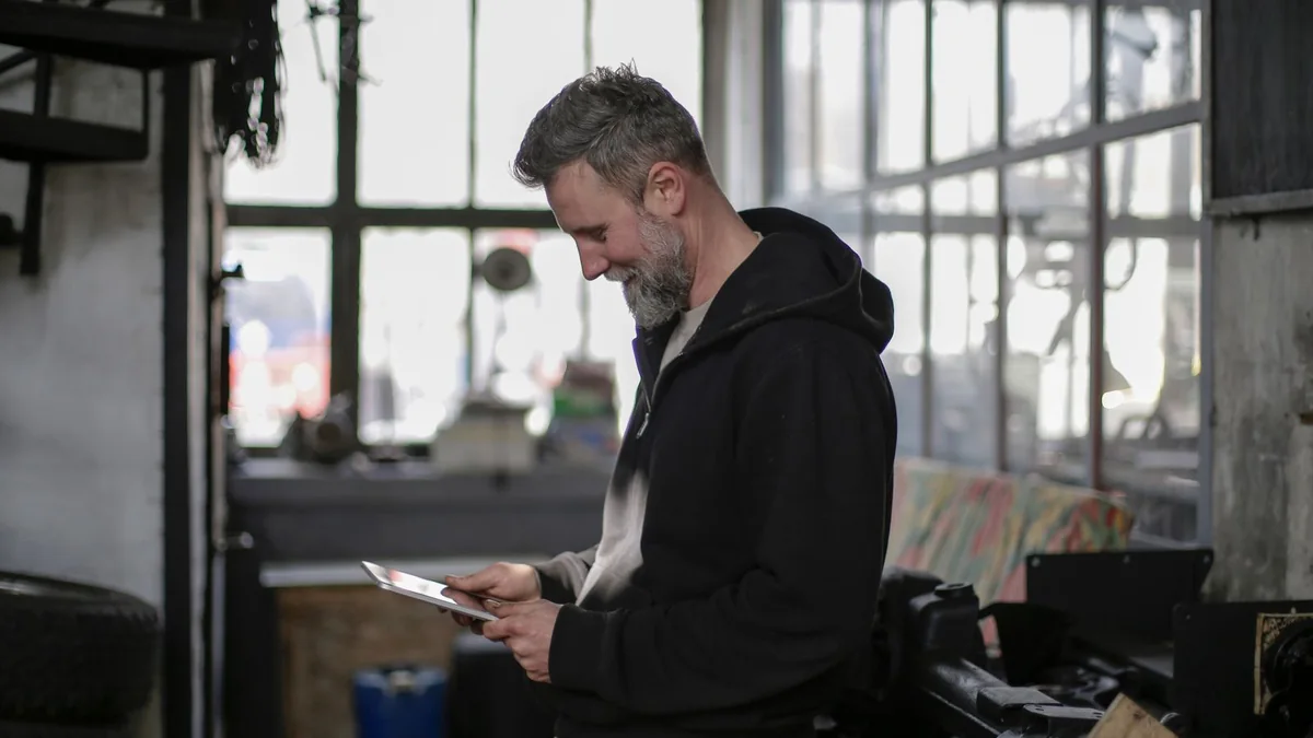 A garage owner checks a tablet in his shop, from our GHL maintenance retainer guide
