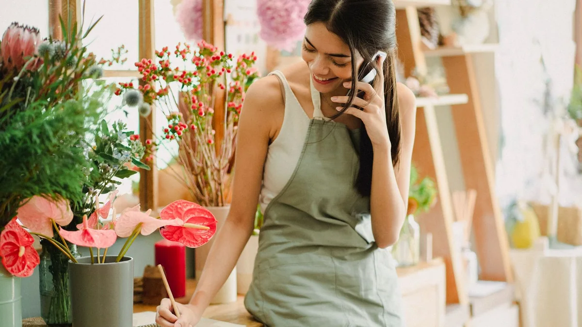 A florist takes notes during a phone call, from our GHL maintenance retainer guide