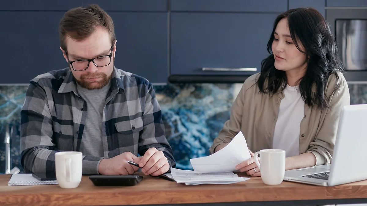 A couple going over a bill at their kitchen table, from our GHL sign up guide