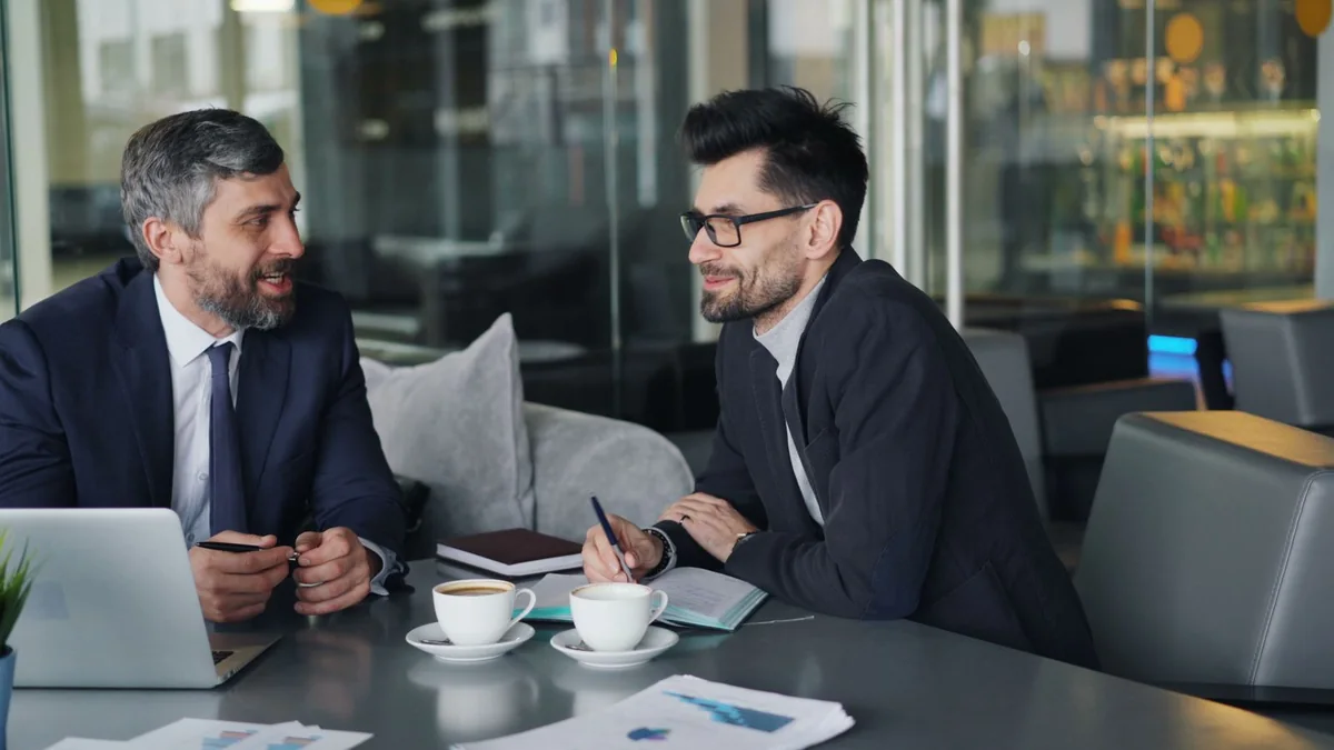 Two business partners comparing plans over coffee, from our GHL sign up guide