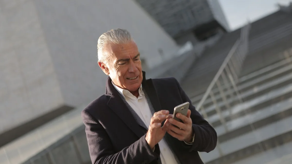 An older business owner checks his phone on the office stairs, from our GoHighLevel billing guide