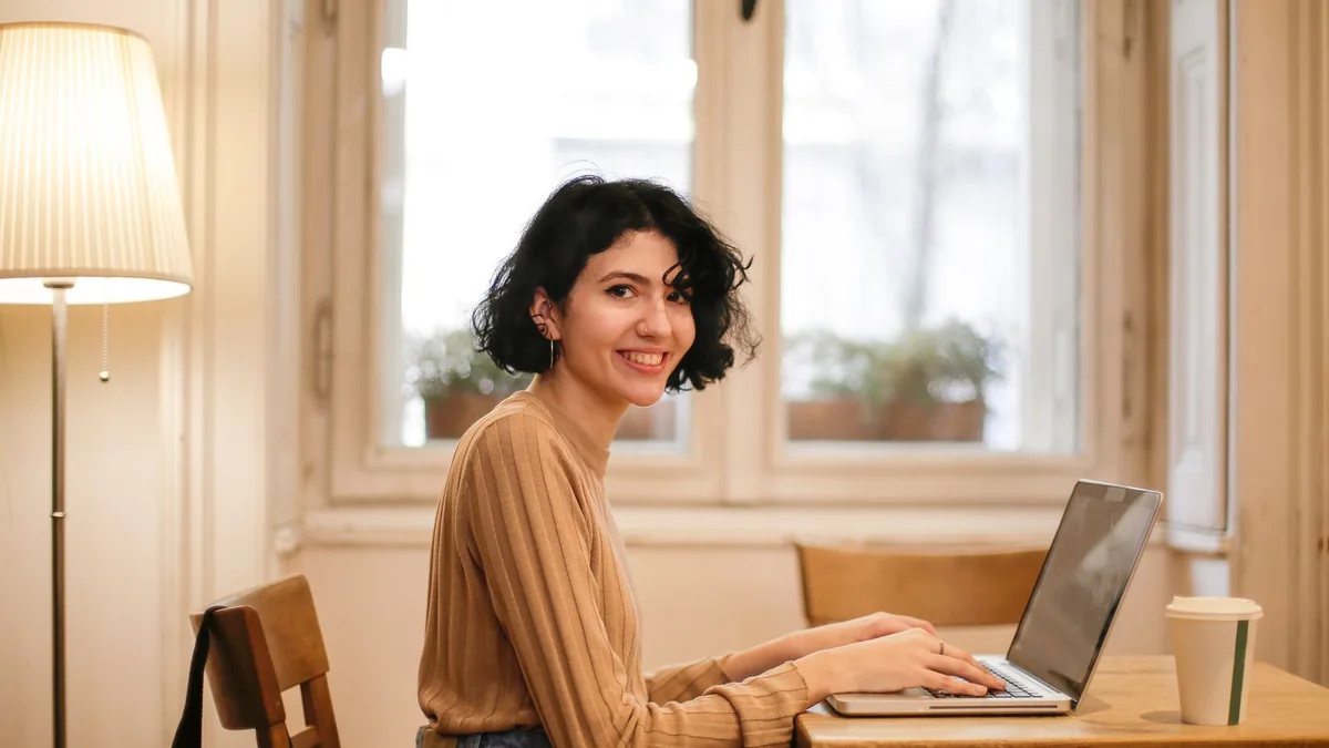 A business owner works on her laptop at a cafe table, from our GoHighLevel dashboard guide