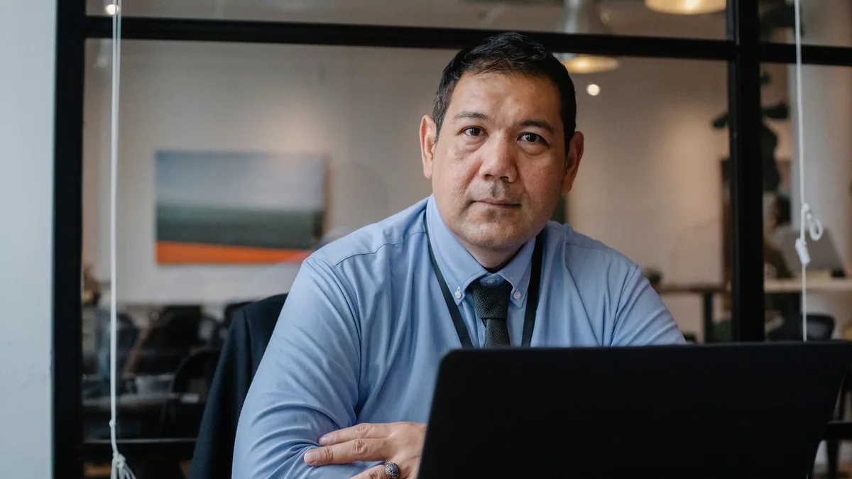 An office manager at his laptop with a coffee mug, from our GoHighLevel dashboard guide