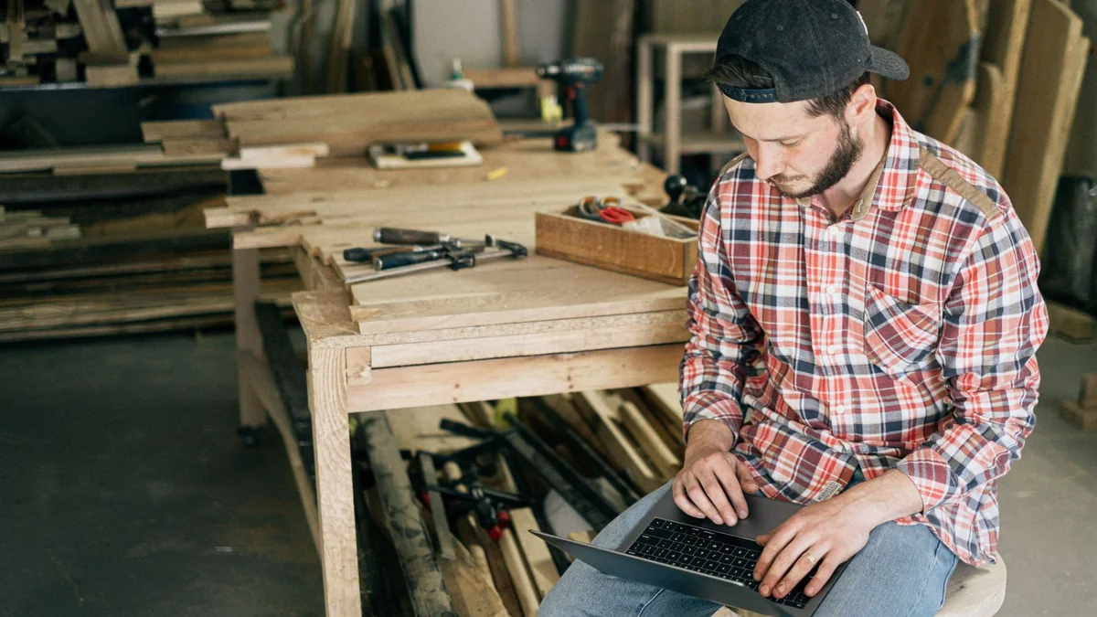 A carpenter checks his laptop in the workshop, from our GoHighLevel dashboard guide