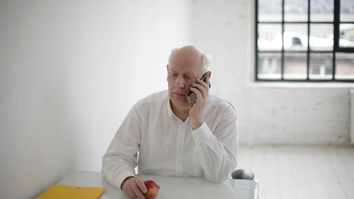 An older business owner on a phone call at his desk, from our GoHighLevel pipeline guide