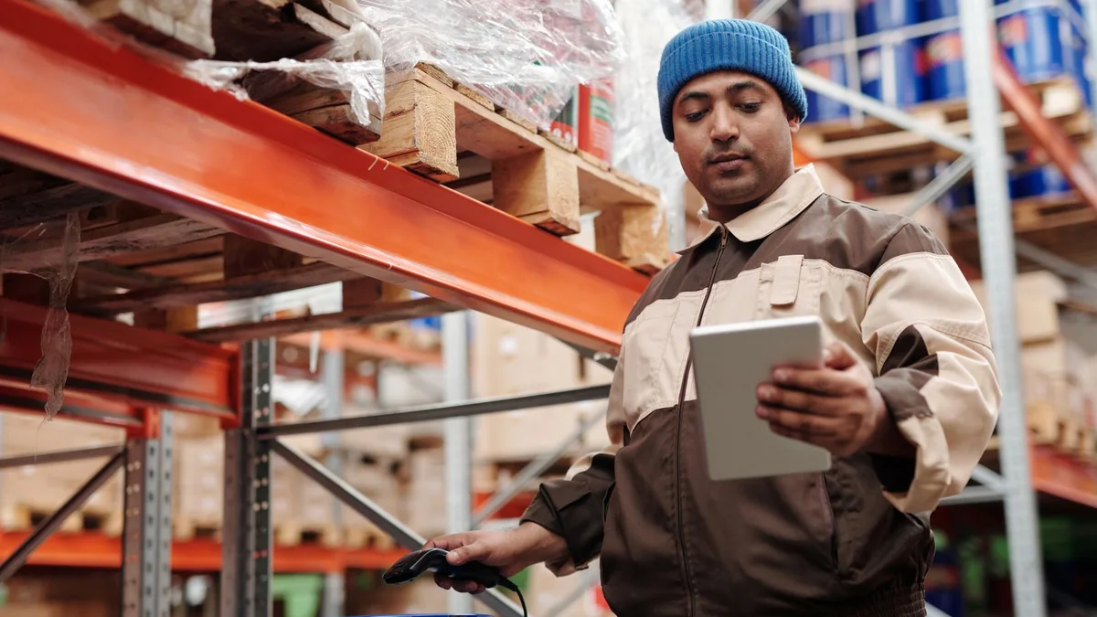 A warehouse manager checks a tablet between shelves, from our GoHighLevel pipeline guide