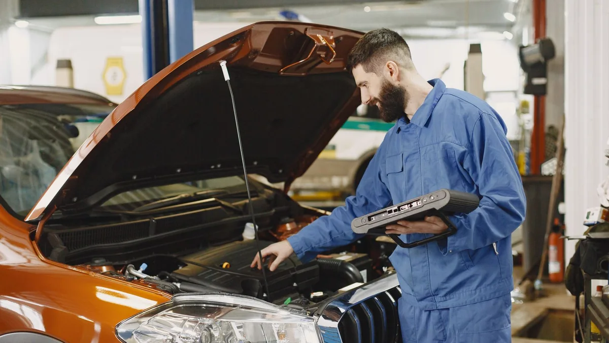 A mechanic reads a tablet beside an open engine bay, from our GoHighLevel pipeline guide
