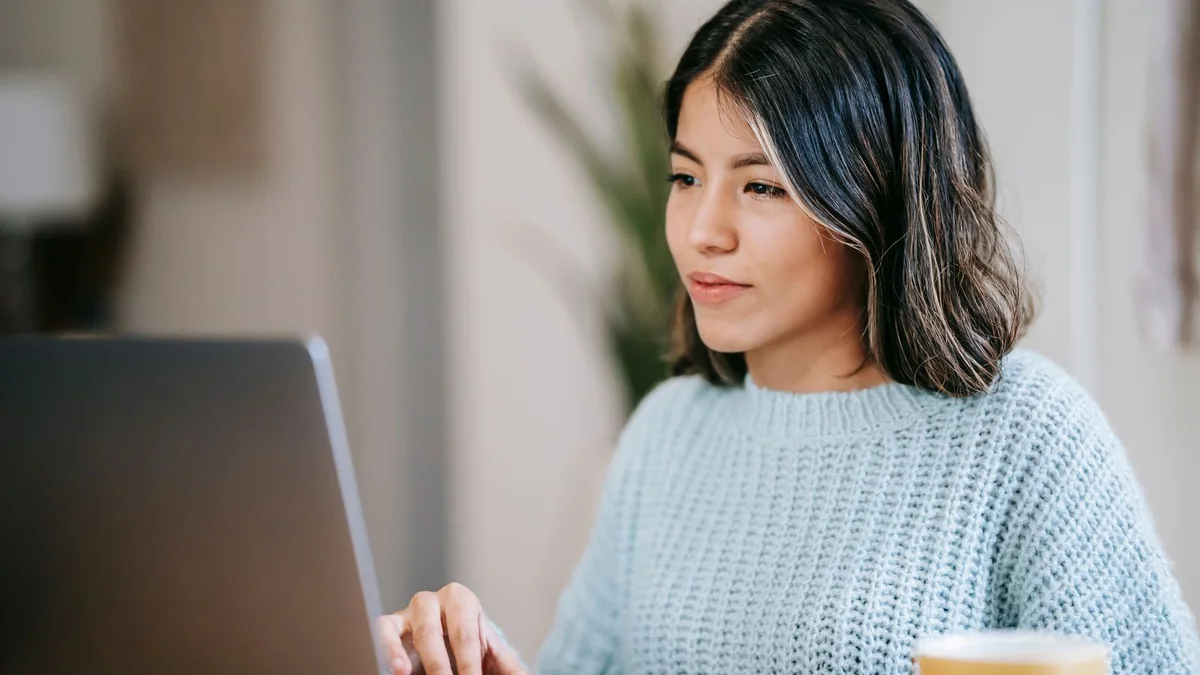 A marketer works on her laptop at a cafe, from our GoHighLevel reporting guide