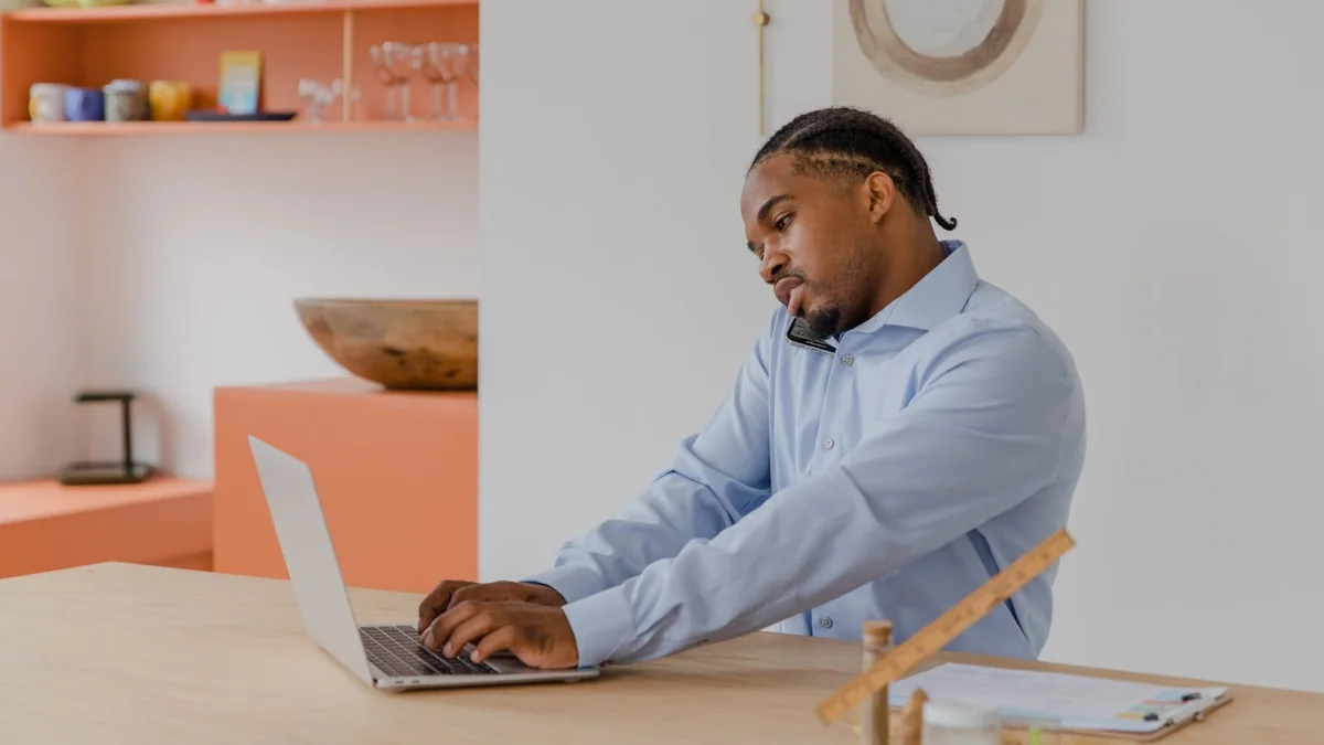 A business owner works at his laptop by the window, from our GoHighLevel reporting guide