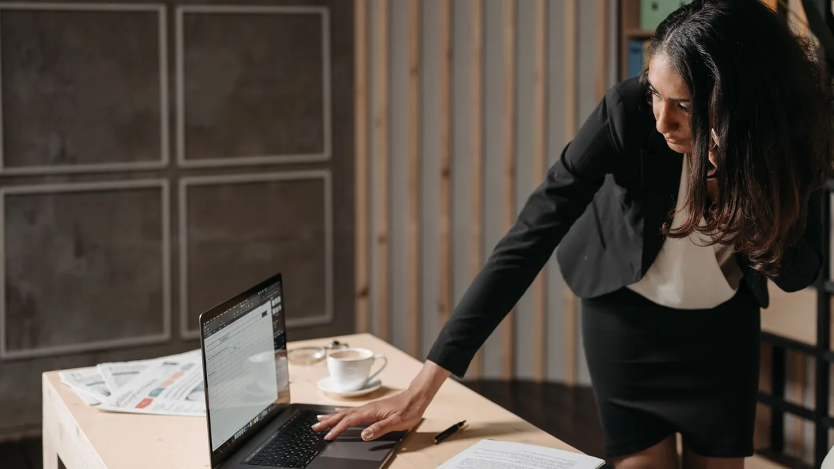 A business owner leans in to check her laptop, from our GoHighLevel reporting guide