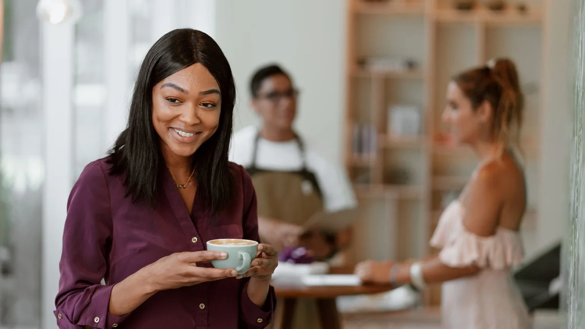 A cafe owner smiles over a cup of coffee, from our GoHighLevel reporting guide