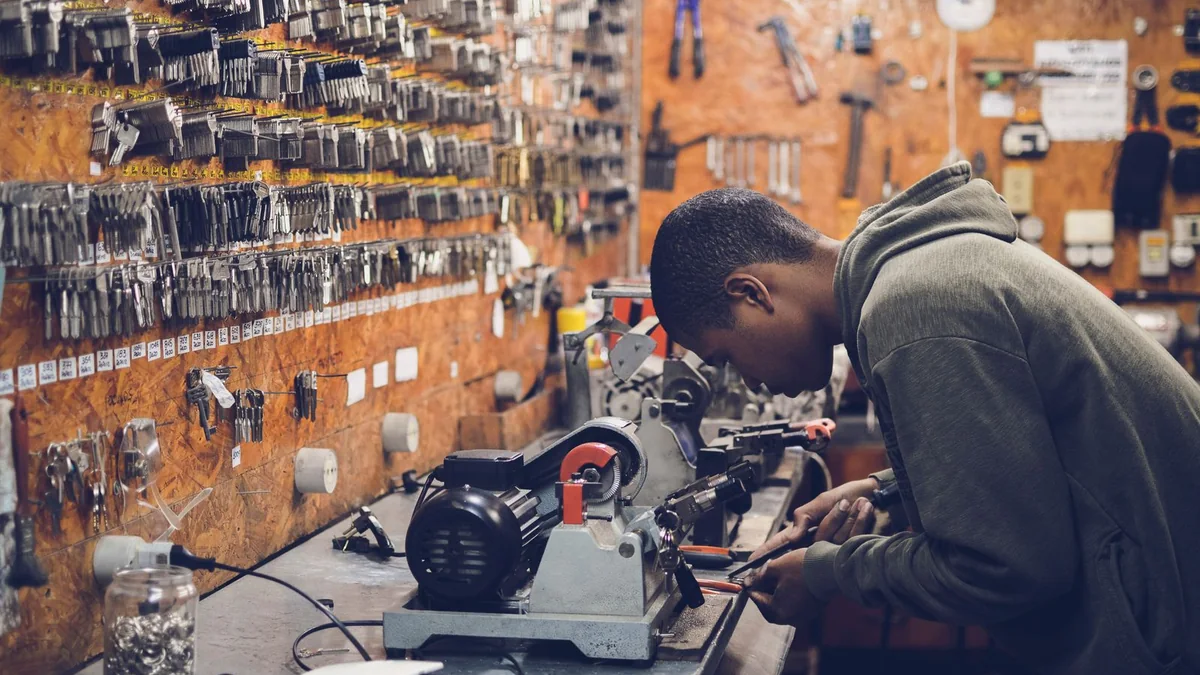 A shop owner works at a key-cutting bench in his workshop, from our GoHighLevel support guide