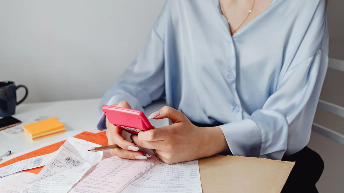 A business owner adds up bills with a calculator, from our GoHighLevel support guide