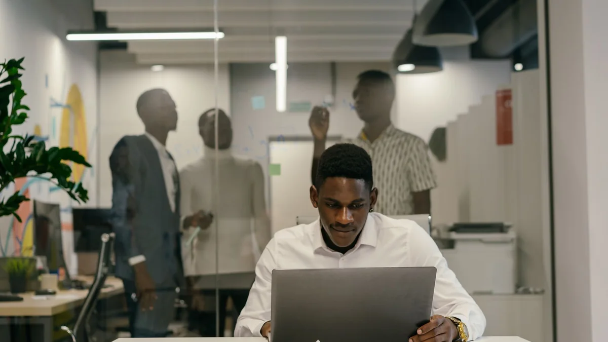 A business owner at his laptop in a shared office, from our HighLevel AI pricing guide