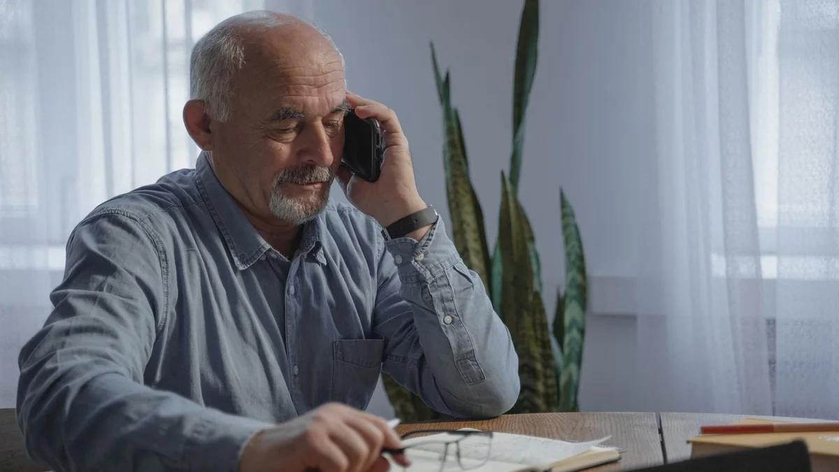 An older business owner takes notes during a phone call, from our HighLevel AI pricing guide