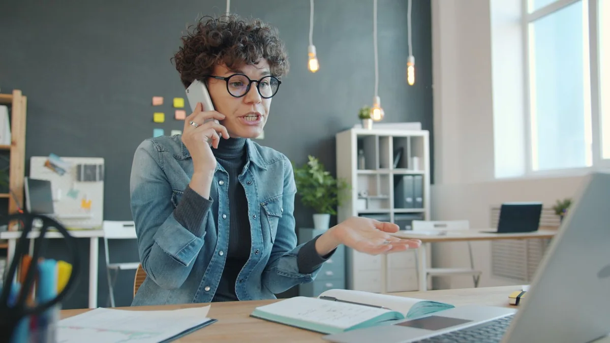 A business owner on a phone call in her office, from our HighLevel AI pricing guide