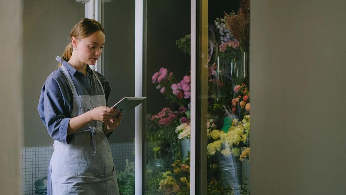 A florist reads a tablet in her shop, from our import contacts guide
