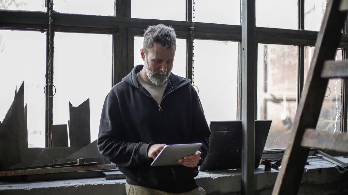 A garage owner reads a tablet in his workshop, from our import contacts guide