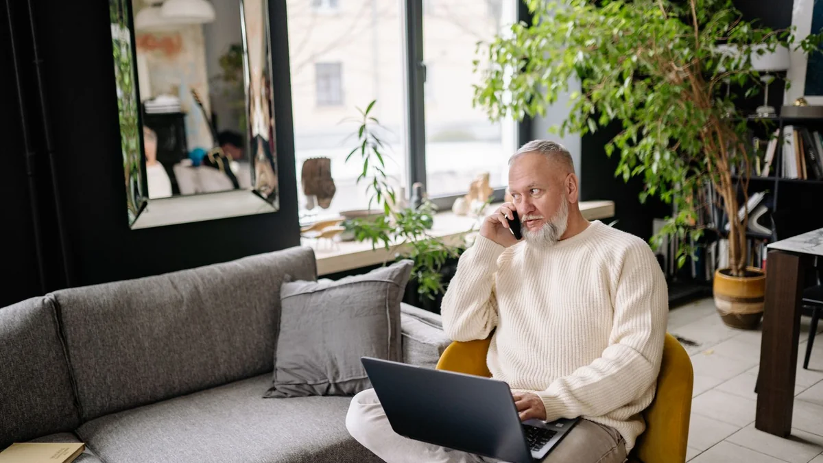 An older business owner works on his laptop from the sofa, from our import contacts guide