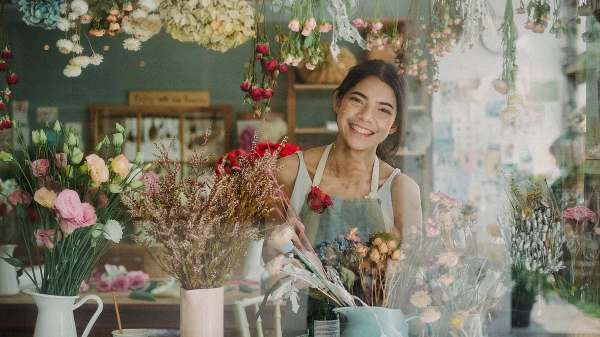 A florist smiles among her flower arrangements, from our reputation management guide