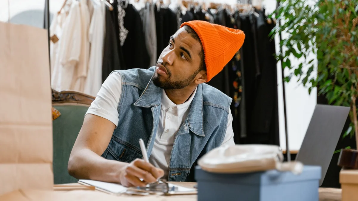 A shop owner writes notes at his boutique desk, from our reputation management guide