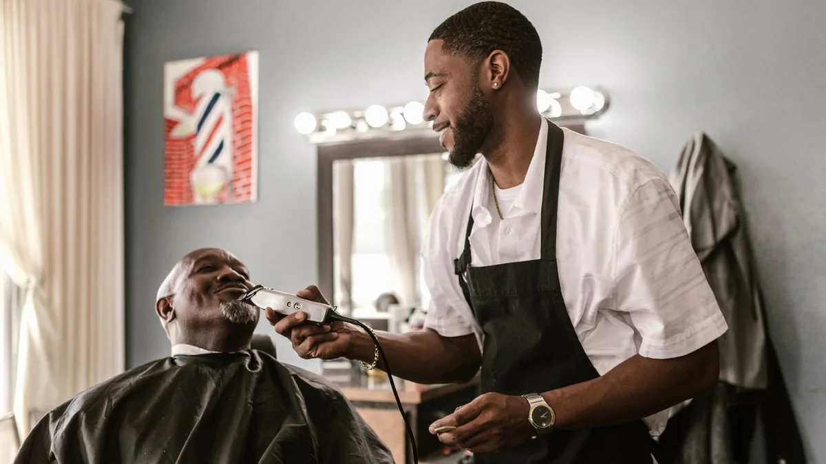 A barber trims a client's beard in his shop, from our reputation management guide